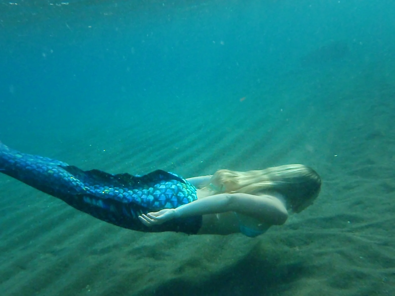 A blue-tailed mermaid gliding underwater