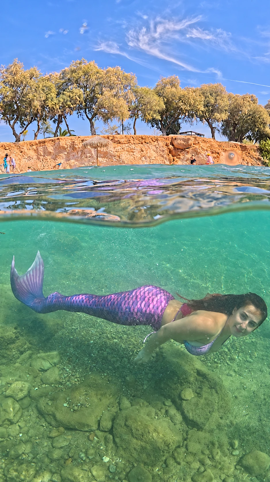 Full split-waterline portrait of a mermaid, sky above and purple tail below